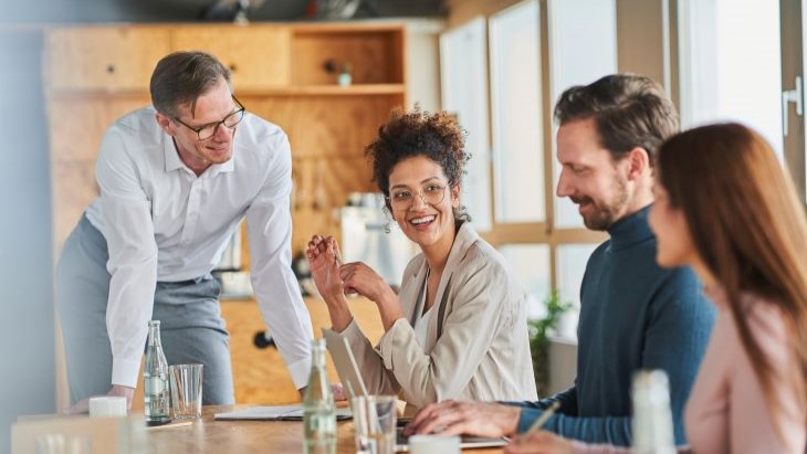 Alt - Group of professionals who look like leaders in a workplace sat down in a meeting setting discussing talent management strategies with optimistic expressions